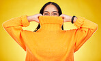 Happy, cover and portrait of a woman with a jersey isolated on a yellow background in a studio. Hiding, winter and a girl holding a jumper up for covering, warmth and bad weather on a backdrop