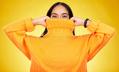 Buy stock photo Happy, cover and portrait of a woman with a jersey isolated on a yellow background in a studio. Hiding, winter and a girl holding a jumper up for covering, warmth and bad weather on a backdrop