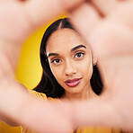 Hands, gesture and portrait of a beautiful woman isolated on a yellow background in a studio. Looking, perspective and the face of a girl in a hand frame for creativity, look through and focus