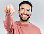 Key, real estate and smile with portrait of man in studio and giving you property, new homeowner or achievement. Rent, pride and purchase with male on white background for house, tenant or investment