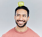 Happy, healthy and an Asian man thinking of an apple isolated on a white background in a studio. Smile, idea and a Chinese guy with a fruit for nutrition, diet and organic wellness on a backdrop