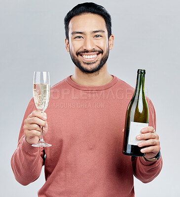 Buy stock photo Portrait, champagne and cheers with a man in studio on a gray background holding a bottle for celebration. Glass, alcohol and toast with a handsome young man celebrating the new year tradition