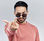 Hand, middle finger and portrait of man in studio cool, attitude and posing with gesture against grey background. Face, rebel and emoji by asian male edgy, expression and personality while isolated