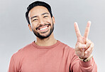 Portrait, smile and Asian man with peace sign in studio isolated on a gray background. Face, v emoji and happy, smiling or excited, young and confident male model with hand gesture or peaceful symbol