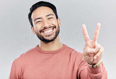 Buy stock photo Portrait, smile and Asian man with peace sign in studio isolated on a gray background. Face, v emoji and happy, smiling or excited, young and confident male model with hand gesture or peaceful symbol