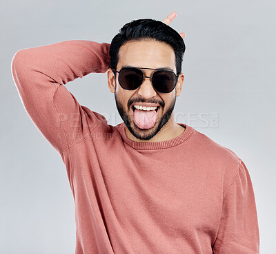 Buy stock photo Portrait, tongue out and Asian man with sunglasses, funny and silly against a grey studio background. Face, Japanese male and guy with funky eyewear, shades and comic with humor and goofy expression 