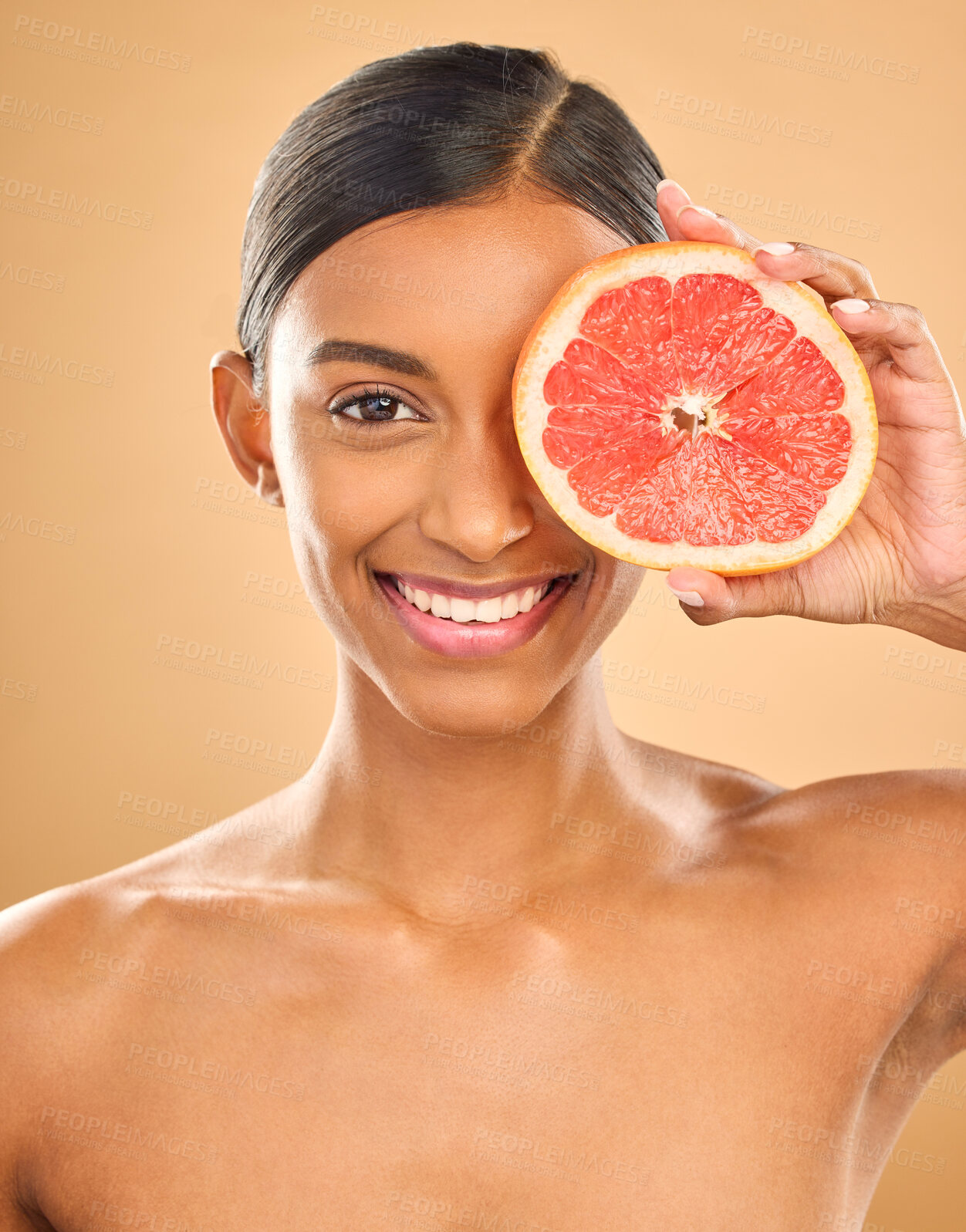 Buy stock photo Face smile, skincare and woman with grapefruit in studio isolated on a brown background. Portrait, natural cosmetics and happy Indian female model with citrus fruit for vitamin c, nutrition or beauty