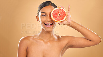 Buy stock photo Face smile, skincare and woman with grapefruit in studio isolated on a brown background. Portrait, natural cosmetics and happy Indian female model with citrus fruit for vitamin c, nutrition or beauty