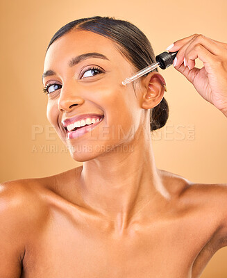 Buy stock photo Face, skincare serum and happy woman in studio isolated on a brown background. Dermatology, cosmetics and smile of Indian female model with hyaluronic acid, retinol or essential oil for healthy skin.