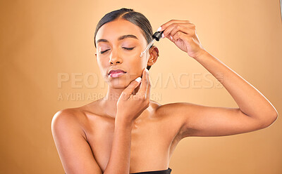 Buy stock photo Face, skincare serum and woman with eyes closed in studio isolated on brown background. Dermatology, cosmetics and Indian female model apply hyaluronic acid, retinol or essential oil for healthy skin