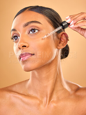 Buy stock photo Face, skincare serum and woman in studio isolated on a brown background. Dermatology cosmetics, thinking and Indian female model with hyaluronic acid, beauty retinol or essential oil for healthy skin