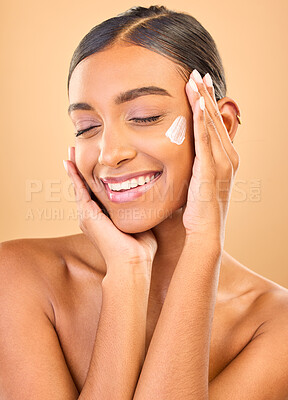 Buy stock photo Face, skincare smile and woman with cream in studio isolated on a brown background. Dermatology cosmetics, eyes closed and happy Indian female model with lotion, creme or moisturizer for skin health.