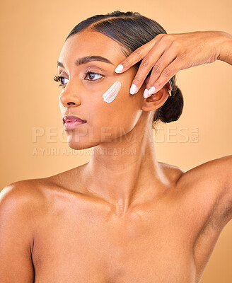 Buy stock photo Face, skincare idea and woman with cream in studio isolated on a brown background. Dermatology, cosmetics and thinking Indian female model with lotion, beauty creme or moisturizer for skin health.