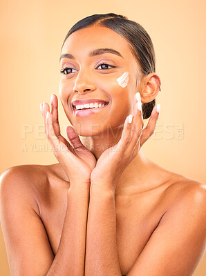Buy stock photo Face, skincare smile and woman with cream in studio isolated on a brown background. Dermatology cosmetics, thinking and happy Indian female model apply lotion, creme and moisturizer for healthy skin.