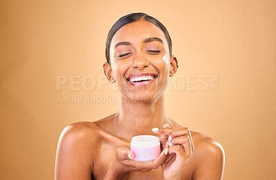 Buy stock photo Face, skincare and woman with cream jar in studio isolated on a brown background. Dermatology cosmetics, funny and happy Indian female apply lotion, creme and moisturizer product for healthy skin.