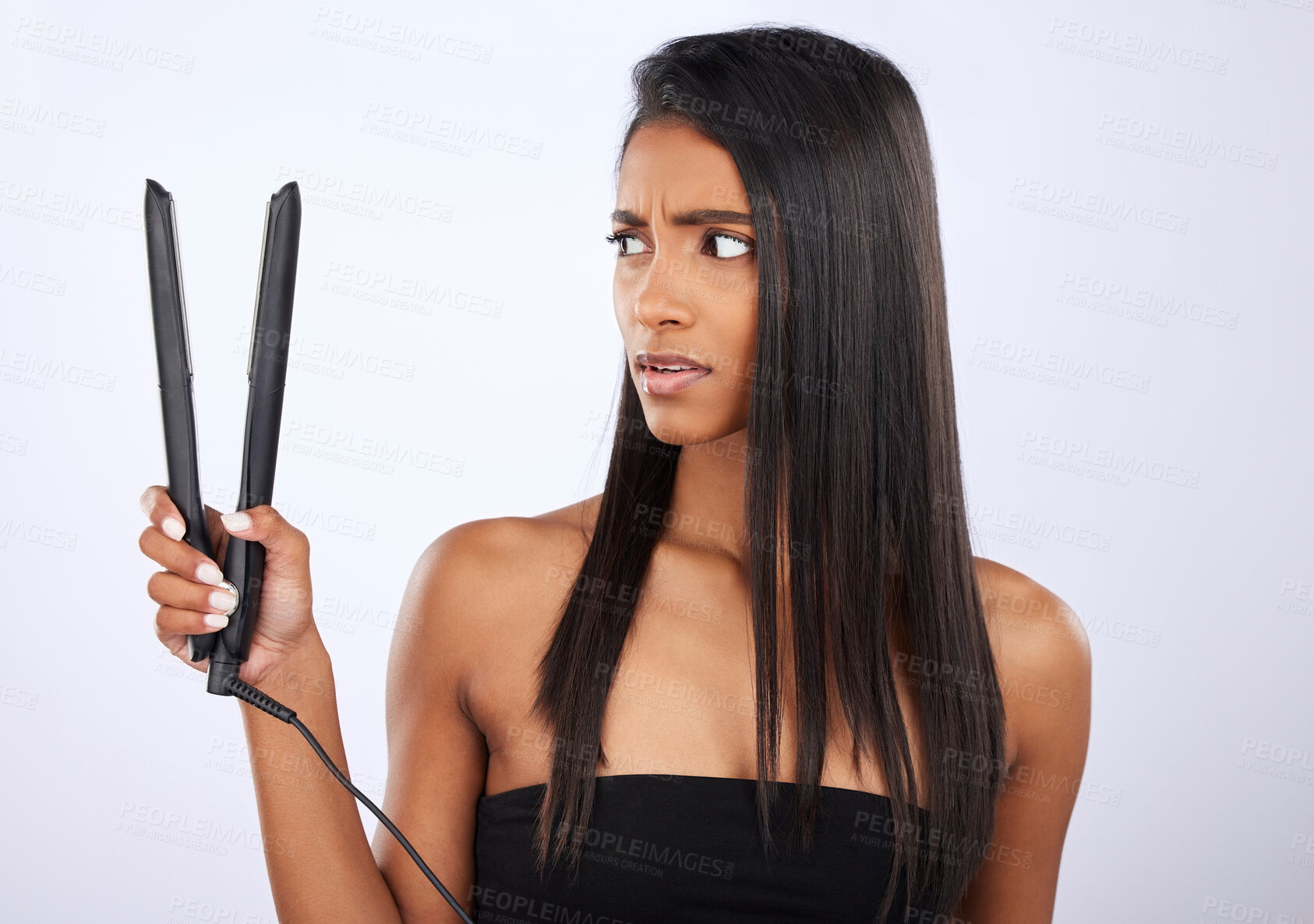 Buy stock photo Angry, woman or hair straightener for beauty self care or treatment in studio on white background. Unhappy, frustrated Indian girl model or salon equipment for ironing in grooming routine for styling