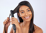 Beauty, health and woman with hair straightener in studio for a straight, long and healthy hairstyle. Happy, smile and portrait of female model with flat iron after hair treatment by gray background.