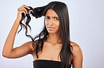 Woman, problem or bad hair care portrait in studio for unhealthy damage, trouble or frizzy texture. Angry, upset or frustrated Indian girl model in self care cosmetics in grooming on white background