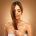 Haircare, smile and woman in studio with hair in hand, strong with bronze texture and salon shine. Happy model, mockup and beauty, healthy straight hairstyle with keratin product on brown background.