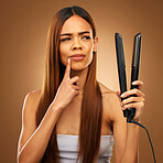 Hair, thinking and woman with flat iron for beauty, wellness and keratin treatment on brown background. Hairdresser mockup, salon and confused girl for healthy growth, haircare texture and cosmetics