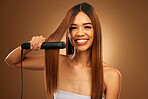 Hair care,  portrait of woman with hot iron and smile for luxury salon treatment on brown background. Beauty, haircut and happy hispanic model with straight hairstyle in studio for haircare styling.