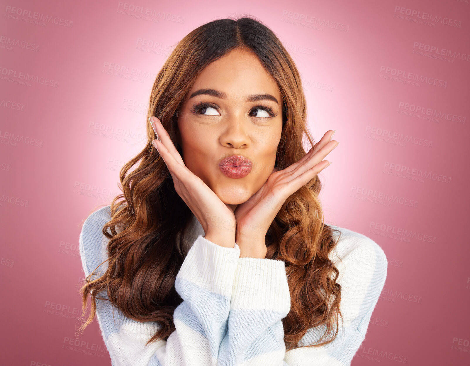 Buy stock photo Beauty, kiss and hands on face of a woman in studio on pink background feeling silly, cute or goofy. Headshot or emoji of young female fashion or skincare model looking playful, excited or flirting