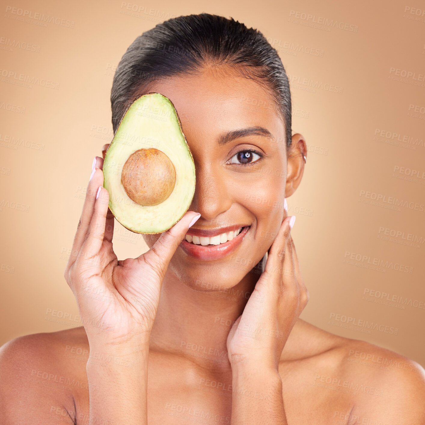 Buy stock photo Portrait, skincare and avocado with a woman in studio on a brown background for natural treatment. Face, food or antioxidants with an attractive young female model holding healthy fruit for nutrition