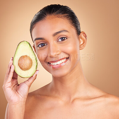 Buy stock photo Portrait, skincare and avocado with a model woman in studio on a brown background for natural treatment. Face, food or antioxidants with an attractive young female holding healthy fruit for nutrition