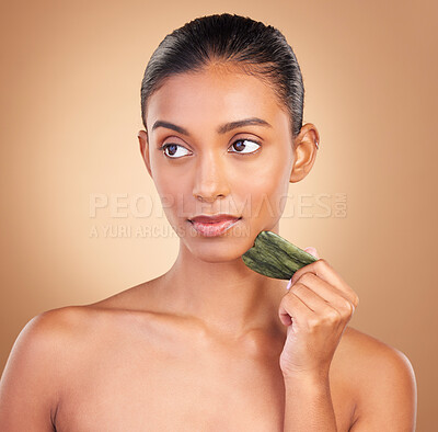 Buy stock photo Skincare, gua sha and face of Indian woman for beauty, facial treatment and wellness with spa tools. Luxury salon, dermatology and serious girl on brown background with cosmetics, massage and stone