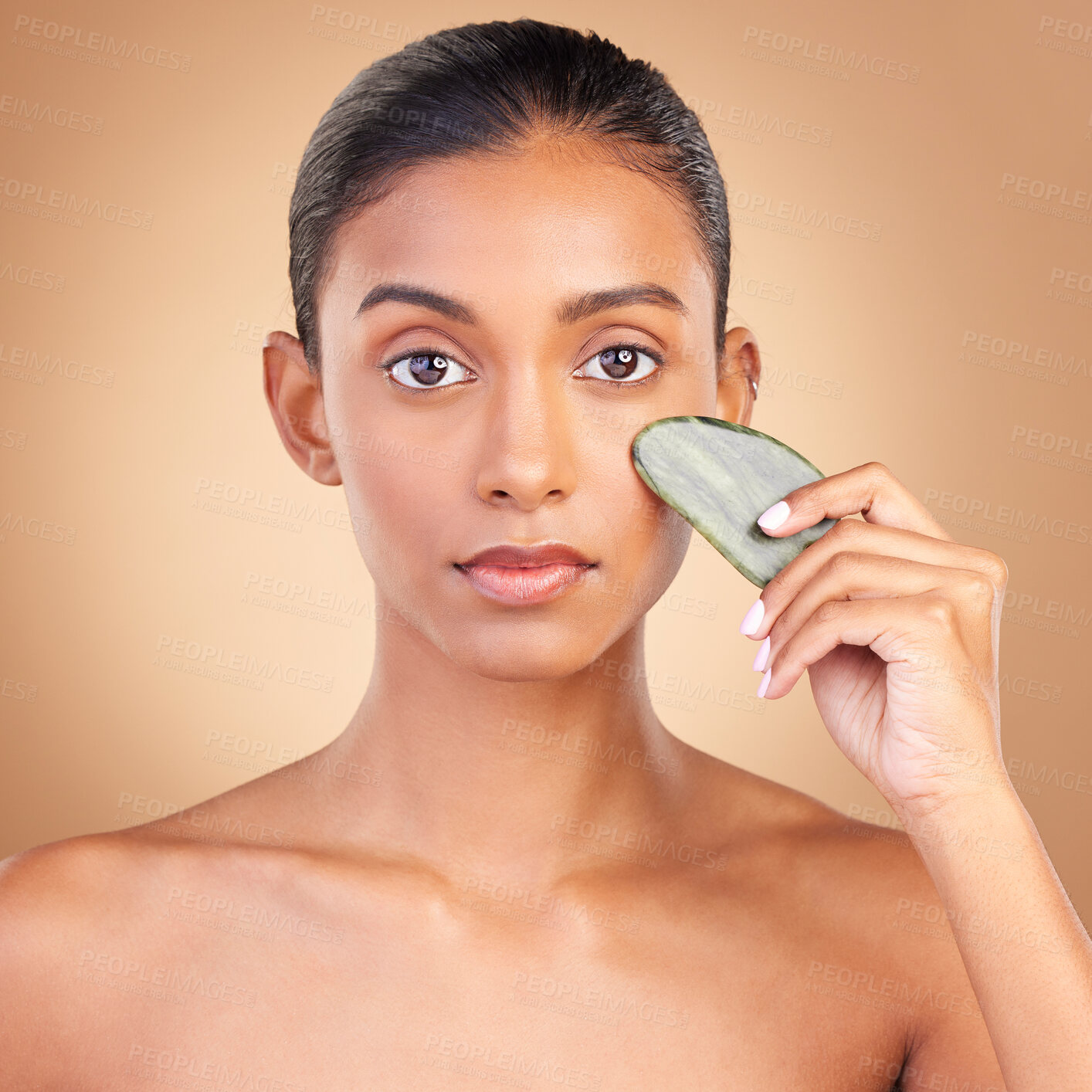 Buy stock photo Skincare, beauty and portrait of Indian woman with gua sha, facial treatment and wellness with spa stone. Salon, dermatology and girl on brown background with cosmetics, face massage and luxury tools