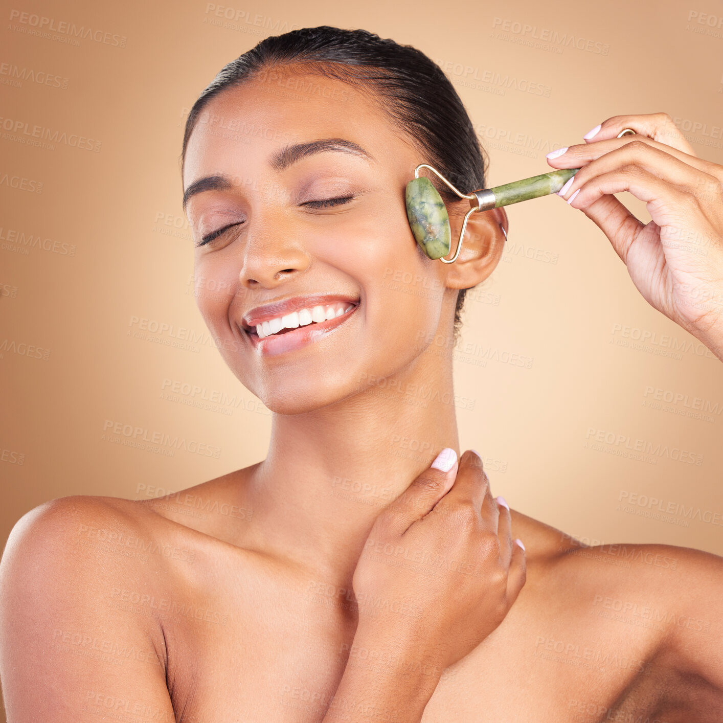 Buy stock photo Facial, massage and skincare with a model woman in studio on a brown background for natural antiaging beauty. Wellness, luxury and product with an attractive young female using a roller for skin lift