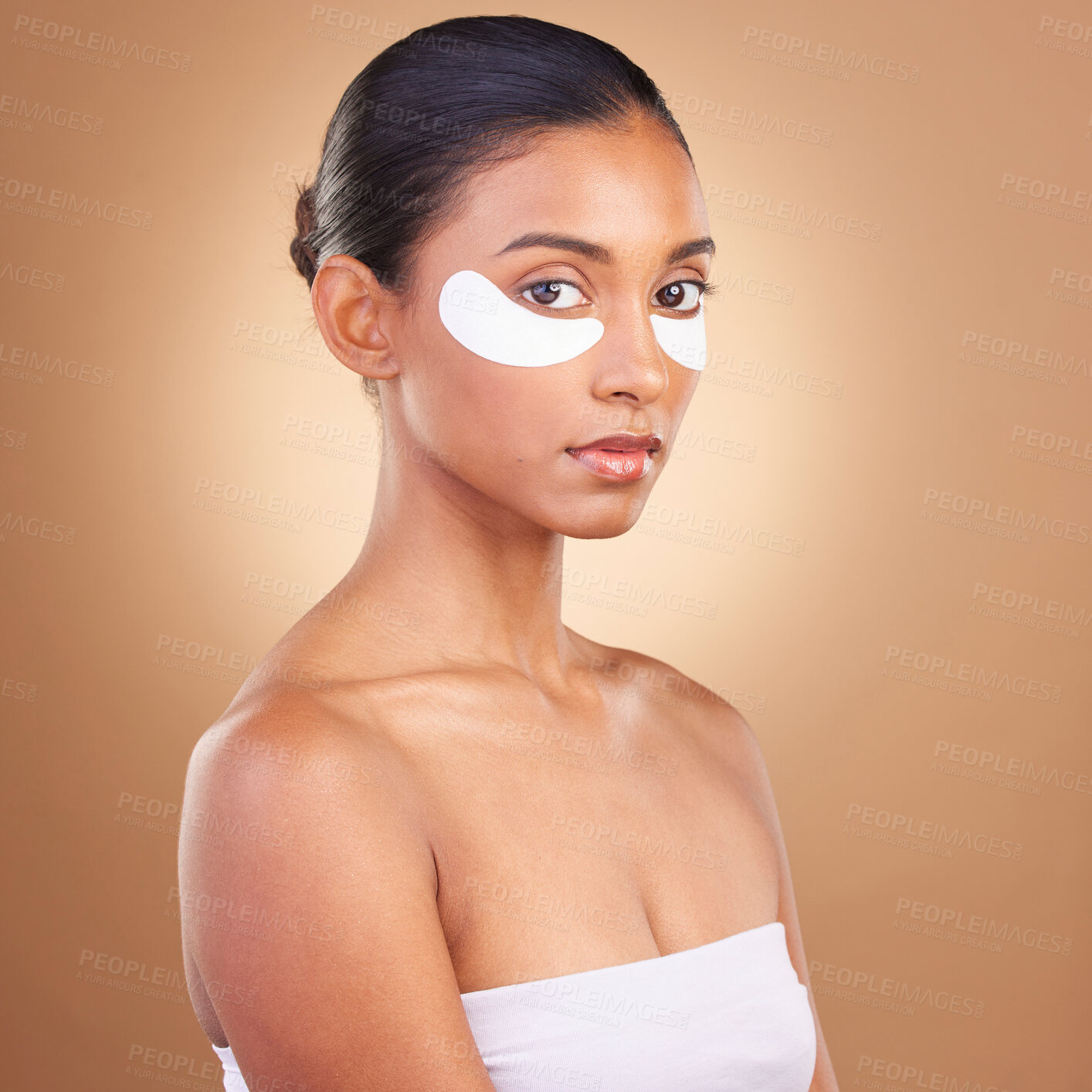 Buy stock photo Skincare, eye patch and beauty with Indian woman for facial, spa treatment and glow. Self care, cosmetics and hydration with female model isolated on brown background for mask, product and youth