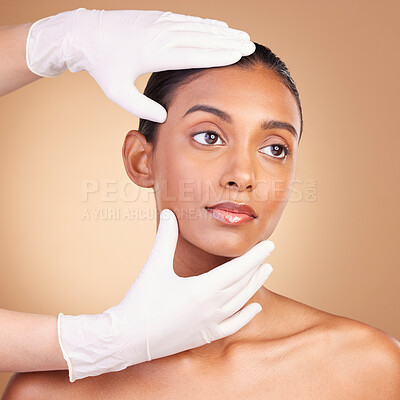 Buy stock photo Beauty, plastic surgery and hands with face of Indian woman in studio for cosmetics and skincare. Spa treatment, dermatology and beautician with female on brown background for consulting