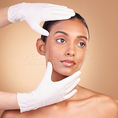 Beauty, plastic surgery and hands with face of Indian woman in studio for cosmetics, skincare and botox. Spa treatment, dermatology and beautician with female on brown background for consulting