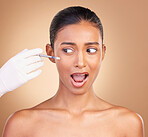 Woman, needle and face in studio for cosmetic, surgery and shock for pain by brown background. Young, model and syringe for facial cosmetics and collagen filler for skincare, dermatology or change