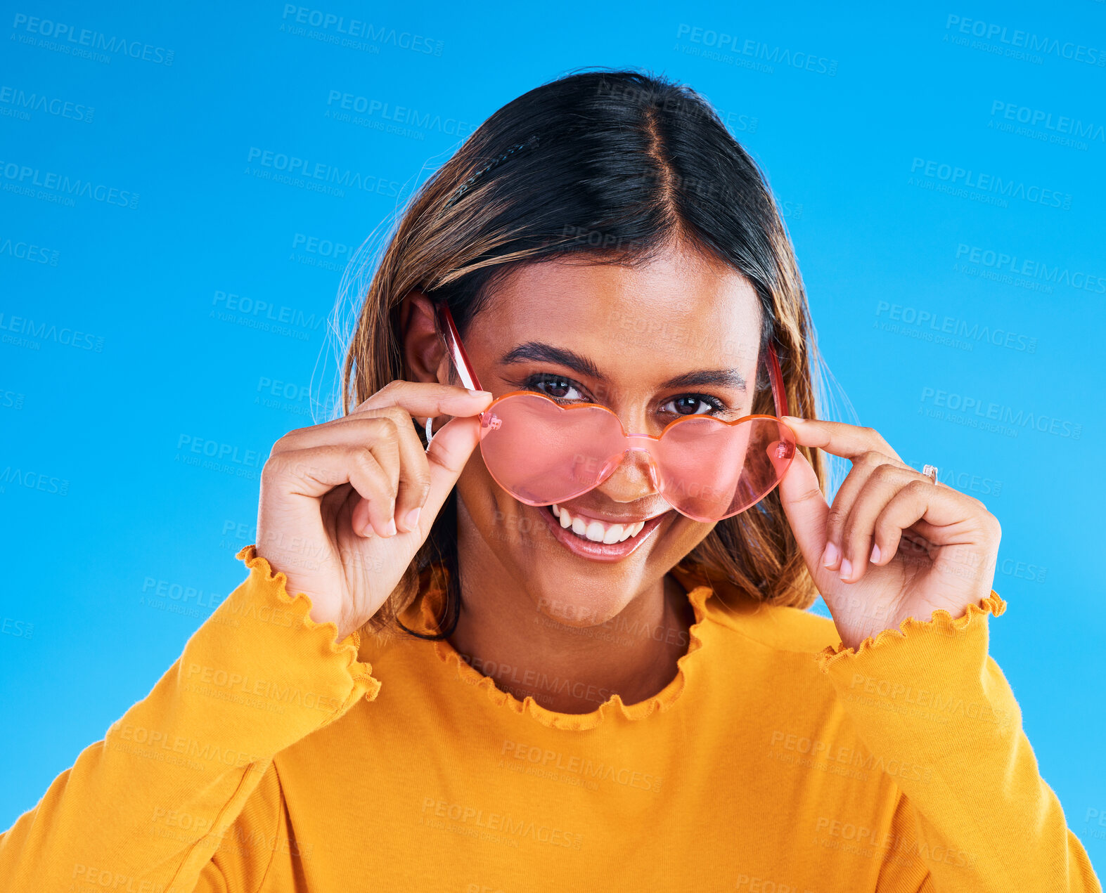 Buy stock photo Fashion portrait, heart glasses and happy woman with young style, designer brand or casual summer outfit. Trendy gen z aesthetic, girl smile and female model face on blue background studio