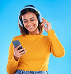 Happy woman, music headphones and phone in studio, blue background and happiness. Female model, smile and mobile for audio, streaming online radio and listening to podcast sound on media subscription