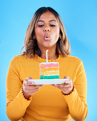 Buy stock photo Birthday cake, woman and blow candles in studio, blue background and celebration. Female model, dessert and wishing at party, flame and special event, rainbow treat or celebrate happiness on backdrop