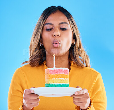 Buy stock photo Birthday cake, candle blowing and woman in a studio with celebration and dessert. Party food, isolated and blue background of a young female with sweet and rainbow treat with surprise and plate