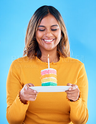 Buy stock photo Birthday cake, happy party and woman in studio, blue background and celebration. Female model, rainbow dessert and candle of special event, sweets and smile to celebrate happiness, wish and surprise