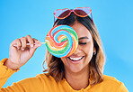 Laughing, lollipop and a woman on a blue background in studio wearing heart glasses for fashion. Funny, candy and sweet with an attractive young female eating a giant snack while feeling silly