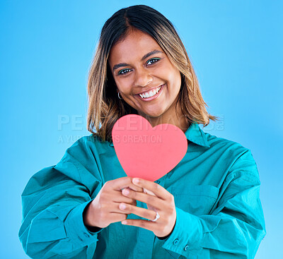 Buy stock photo Paper heart, happy woman and portrait in studio, blue background or backdrop. Smile, female model and shape of love, trust and support of peace, thank you and kindness on valentines day, date or hope
