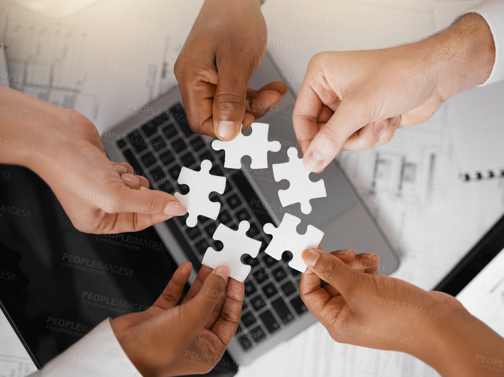 Buy stock photo Hands, puzzle and overhead with a business team in the office, working in collaboration on a project. Teamwork, jigsaw piece and laptop with a diverse group of people at work together from above