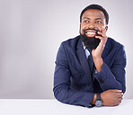 Happy, thinking and a black man sitting by a table isolated on a white background in a studio. Smile, thoughtful and an African businessman with an idea, thought or contemplation on a backdrop