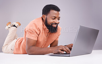 Buy stock photo Happy black man, laptop and studio floor to search social media, online shopping or subscription download. Smile, male model and computer technology for internet, typing email or elearning on website