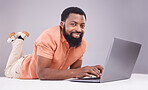 Portrait, black man and laptop on studio floor to search social media, online shopping or subscription download. Happy male model typing on computer technology, internet blogging or elearning website