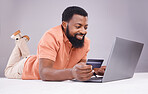 Credit card, black man and smile on laptop in studio for online shopping, digital payment or money investment. Male model, ecommerce and computer sales for finance, fintech budget or internet banking