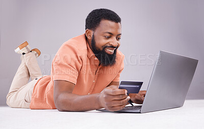 Buy stock photo Credit card, black man and smile on laptop in studio for online shopping, digital payment or money investment. Male model, ecommerce and computer sales for finance, fintech budget or internet banking