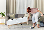 Woman, vacuum and housekeeping on carpet in living room for spring cleaning service, dust or dirt removal at home. Female cleaner lifting table and vacuuming for clean rug, mat or floor in the lounge