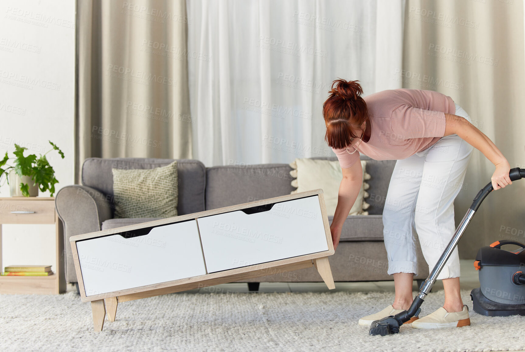 Buy stock photo Woman, vacuum and housekeeping on carpet in living room for spring cleaning service, dust or dirt removal at home. Female cleaner lifting table and vacuuming for clean rug, mat or floor in the lounge